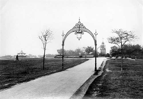 View down ornamental archways at Woodhouse Moor. A drinking fountain donated by Alderman North can be seen. 1897