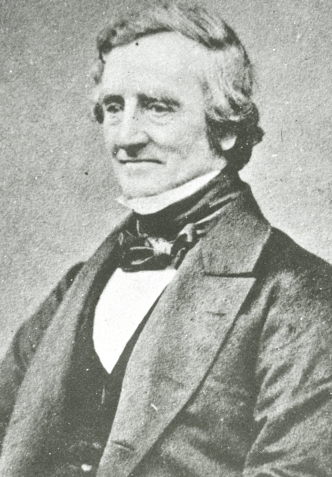 Photograph of James Watson, a middle-aged man, wearing a smart suit and neckerchief. He is clean-shaven.