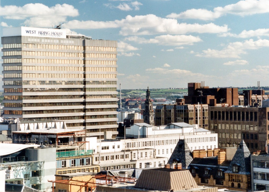 A view of rooftops in Leeds, Large tower blocks, the spire of a church and roofs of smaller buildings are visible.