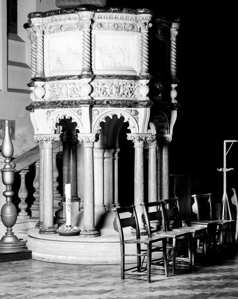 Black and white image of a large pulpit within a church.