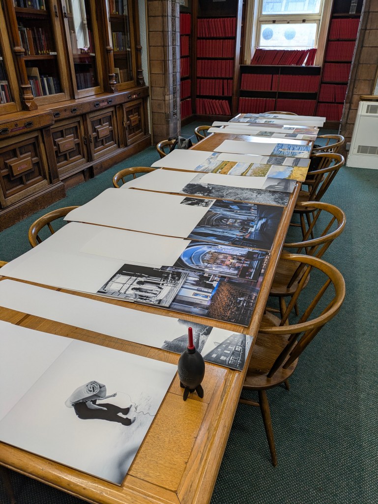 A long table with various photographs laid out on it.