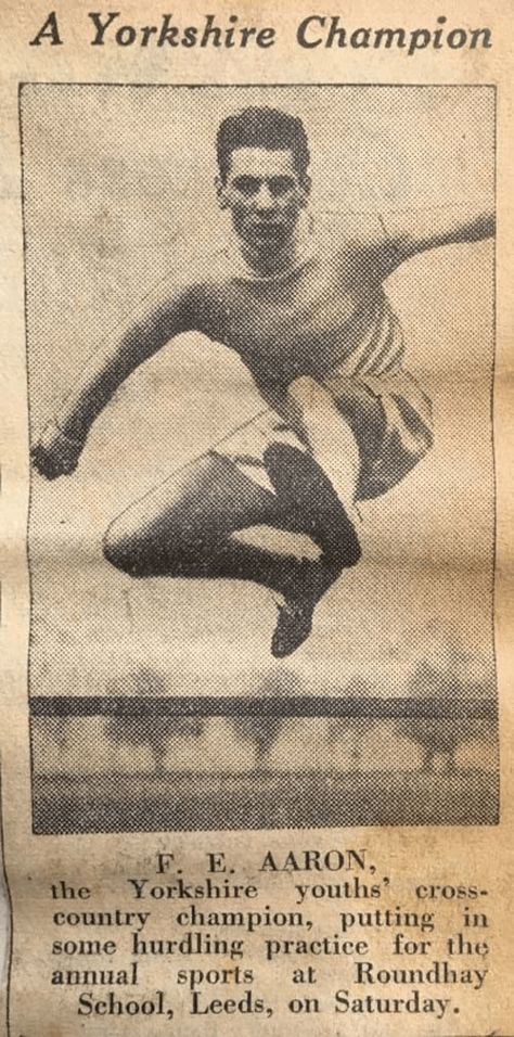 Champion runner Frank Aaron jumps over a hurdle 